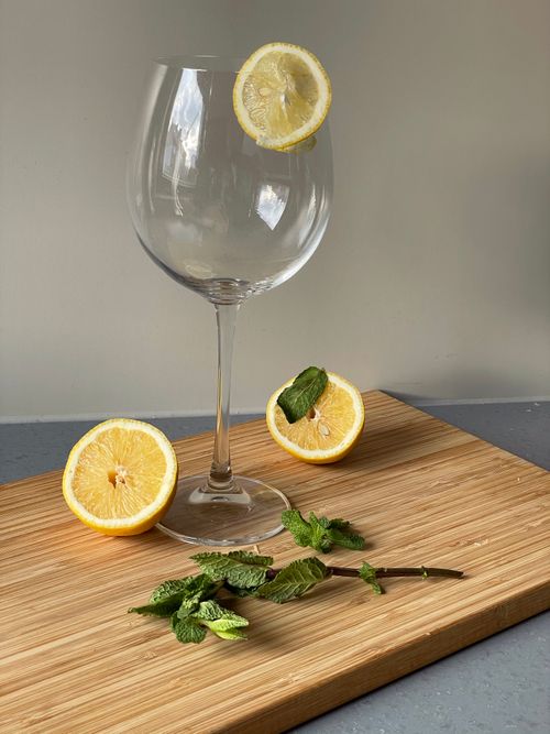 Free Elegant still life with sliced lemon and mint in a wine glass on wooden board. Stock Photo