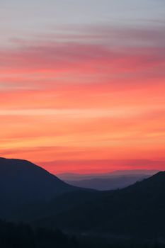 A breathtaking view of a vivid sunset over silhouetted mountains and colorful skies.
