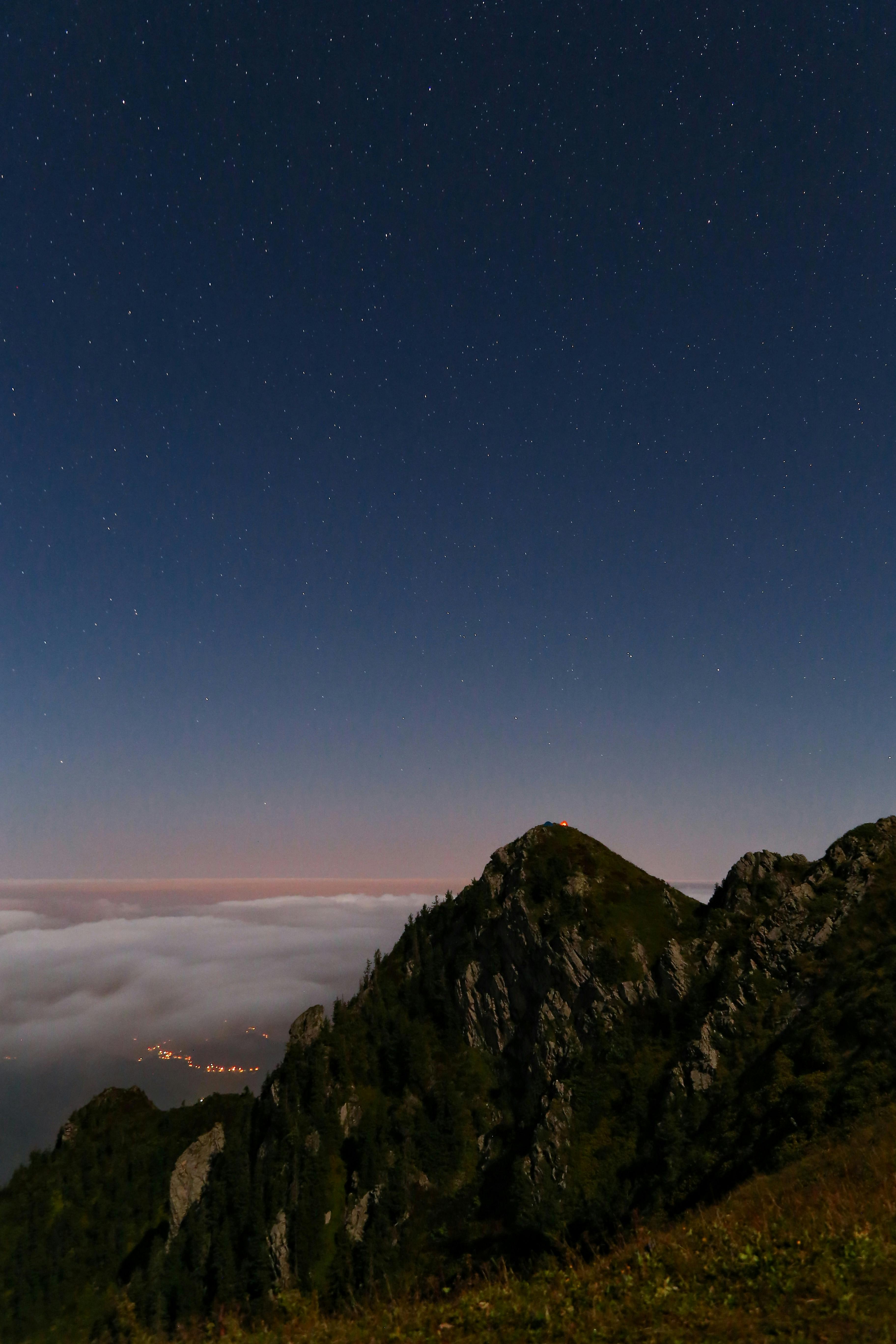 A serene starry sky above rugged mountain peaks at night, creating a tranquil landscape.