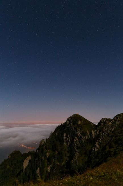 A serene starry sky above rugged mountain peaks at night, creating a tranquil landscape.