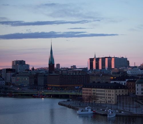 Free Riddarholmen Church and building facades against river with yachts under cloudy sky in evening in Stockholm Sweden Stock Photo