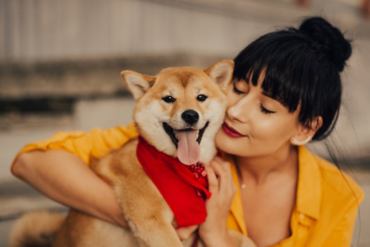 A woman lovingly embraces her Shiba Inu dog, capturing a joyful and affectionate moment.