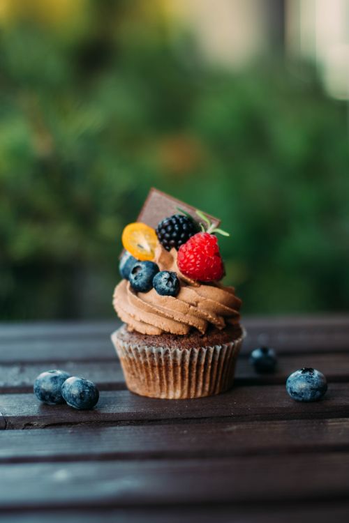 Free Mouthwatering chocolate cupcake topped with fresh blueberries, raspberries, and a chocolate piece. Stock Photo