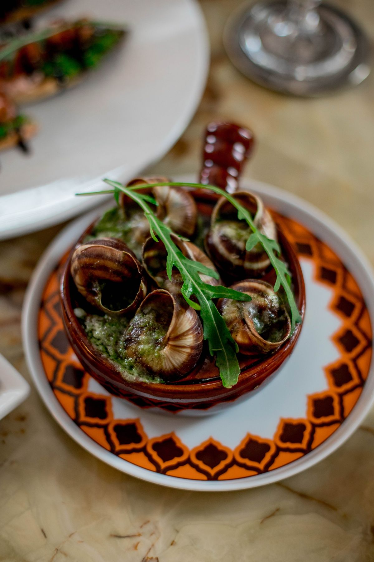 French escargot dish served with fresh herbs on a plate, ready-prepared snails in garlic butter