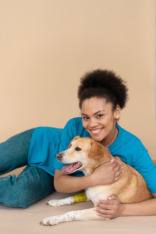 Free Woman in Blue Long Sleeve Shirt Holding Brown Short Coated Dog Stock Photo