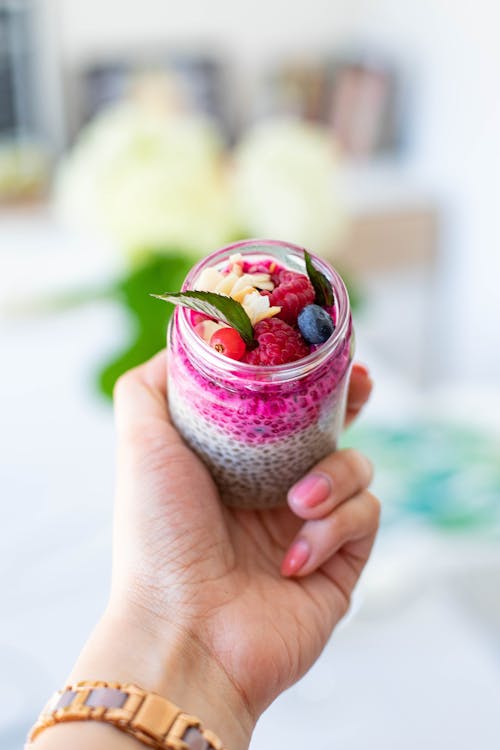 Crop woman showing yogurt with berries