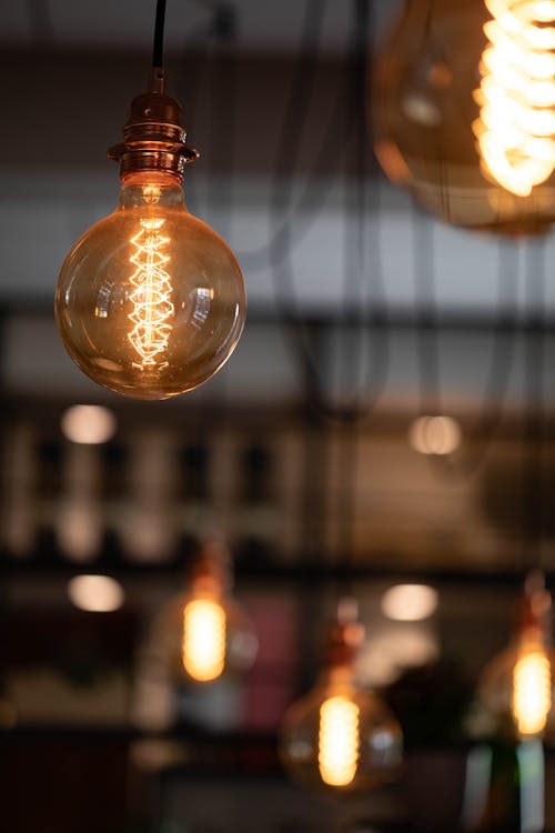 Soft focus of retro electric light bulb hanging on ceiling and illuminating cafeteria