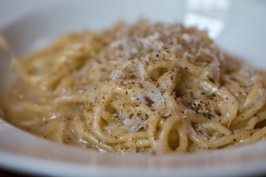 Closeup portion of tasty spaghetti served in bowl with parmesan cheese for lunch