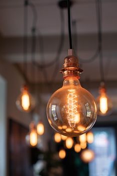 Soft focus of stylish retro lamp glowing with vivid electric light and illuminating cafeteria