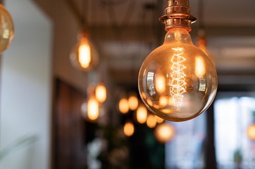 Reflective vintage light bulb shining brightly on blurred background of pub in evening