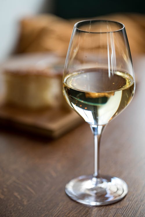 Glass goblet of white wine placed on wooden table during dinner in restaurant