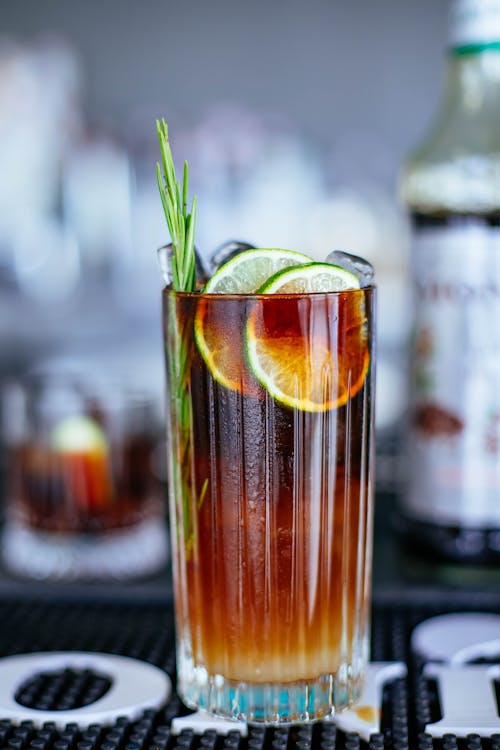 Glass of yummy iced coffee with slices of lime and twig of rosemary served in cafe