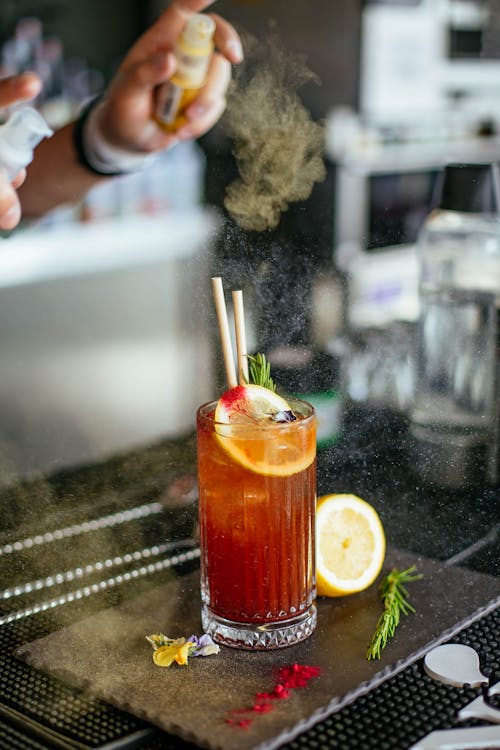 Unrecognizable barista spraying infusion on drink