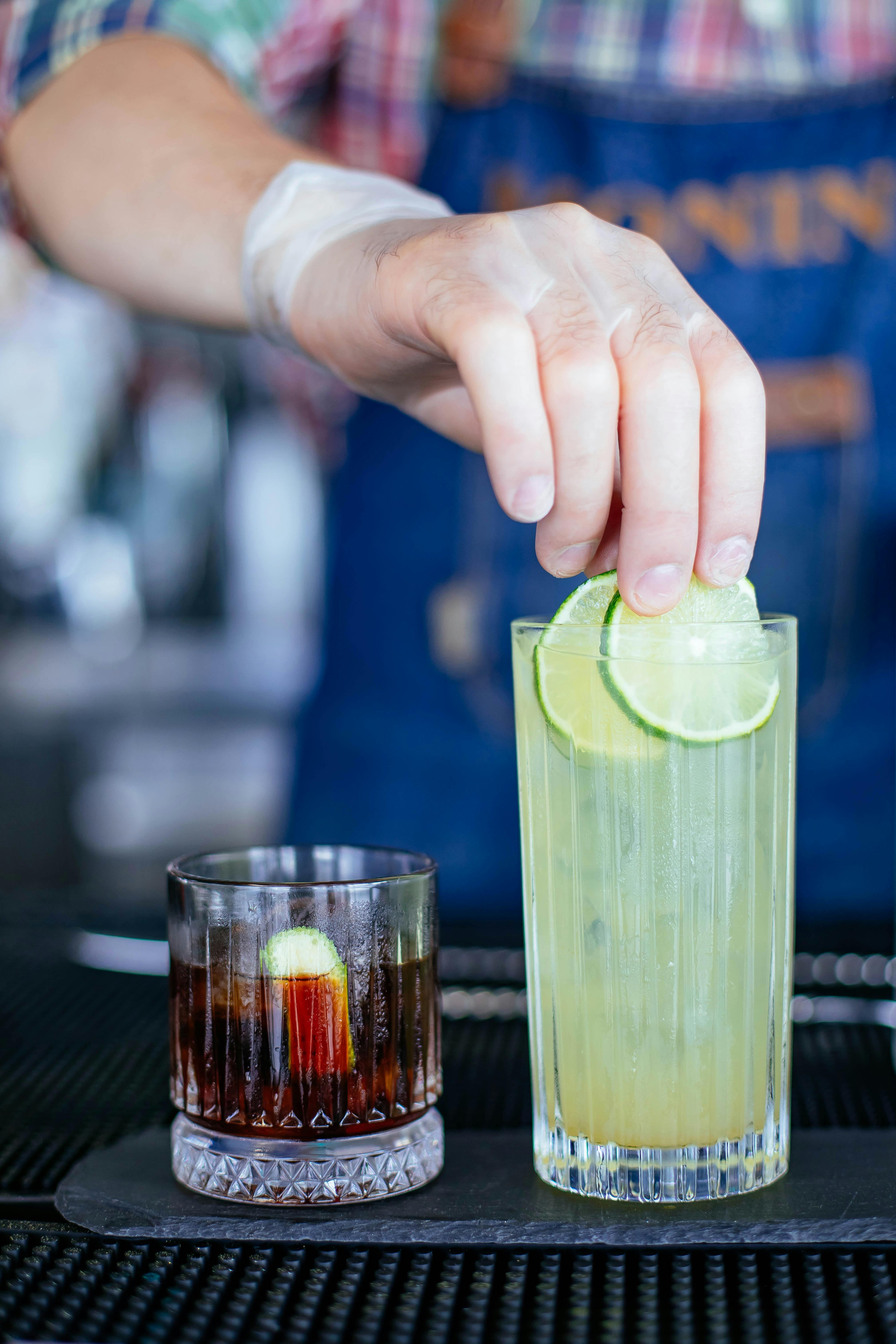 bartender decorating refreshing cocktail with lime