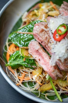 Closeup of delicious funchose salad with meat and sauce in bowl on table
