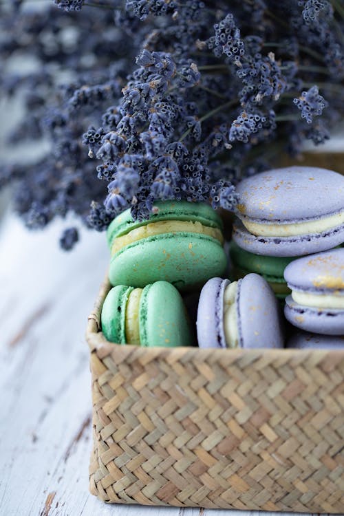 Tasty fresh macaroons with delicate cream in timber wicker box on blurred background