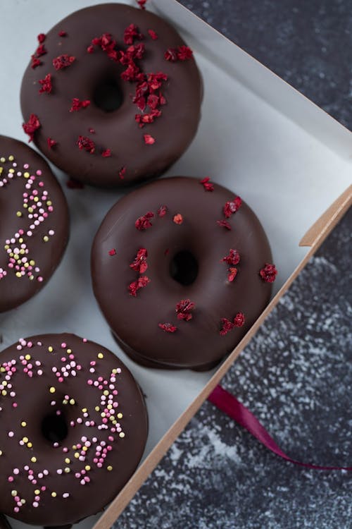 Free Top view of sweet tasty donuts in chocolate glaze covered with many sprinkles in box Stock Photo