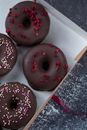 Top view of sweet tasty donuts in chocolate glaze covered with many sprinkles in box
