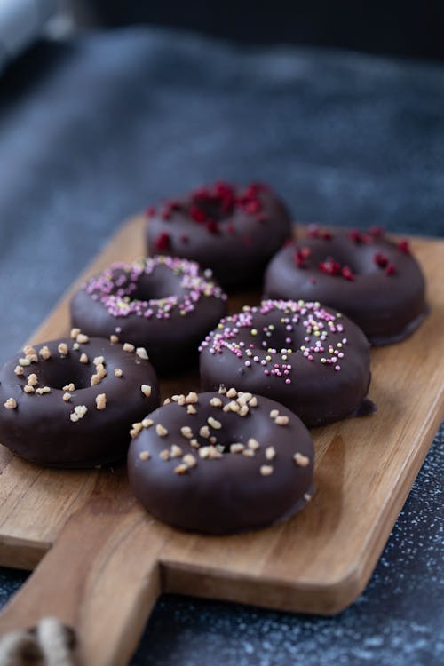 Yummy chocolate donuts placed on wooden cutting board