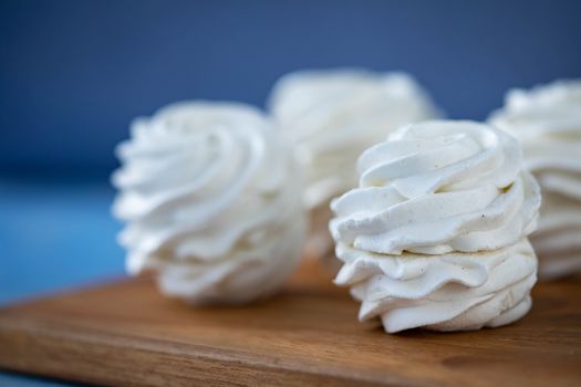 Sweet zephyrs placed on wooden board against blurred background