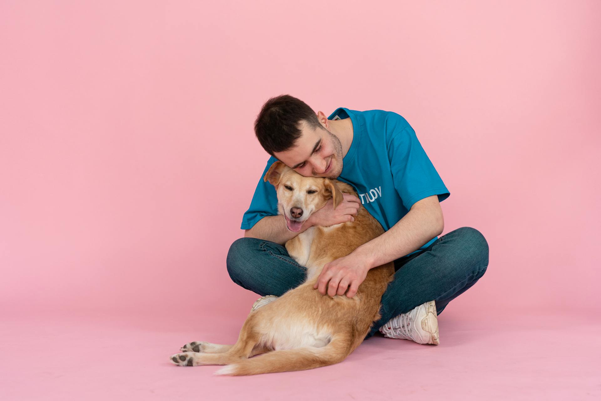 Man Sitting on the Floor while Hugging a Dog