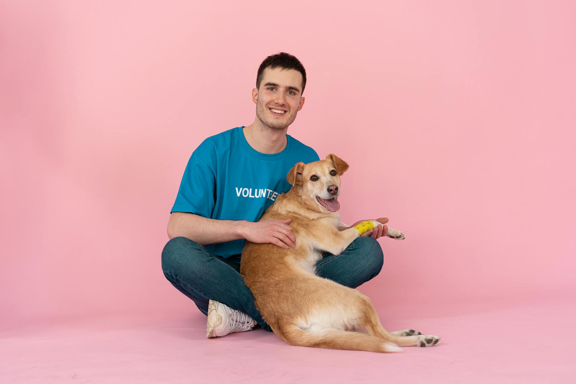 Man in Blue Shirt Sitting on Floor With Dog