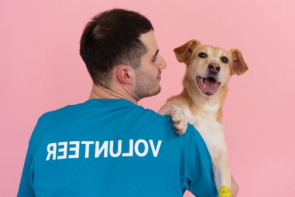 A volunteer holds a joyful dog, showcasing affection and support for pet adoption.