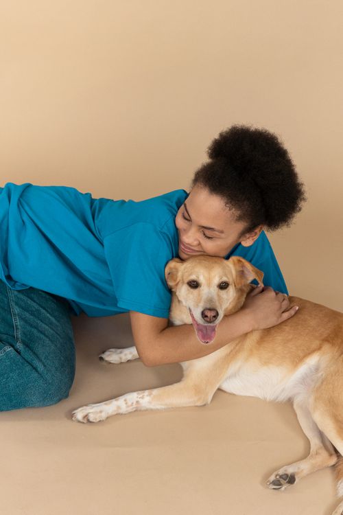 Free Woman happily embracing her pet dog in a studio, showcasing love and companionship. Stock Photo
