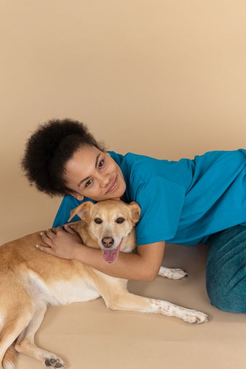 Free Smiling woman with curly hair hugging her dog in studio, showcasing love and companionship. Stock Photo