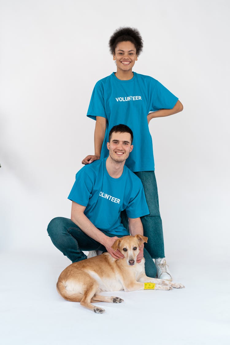 A Man And A Woman Holding A Brown Dog