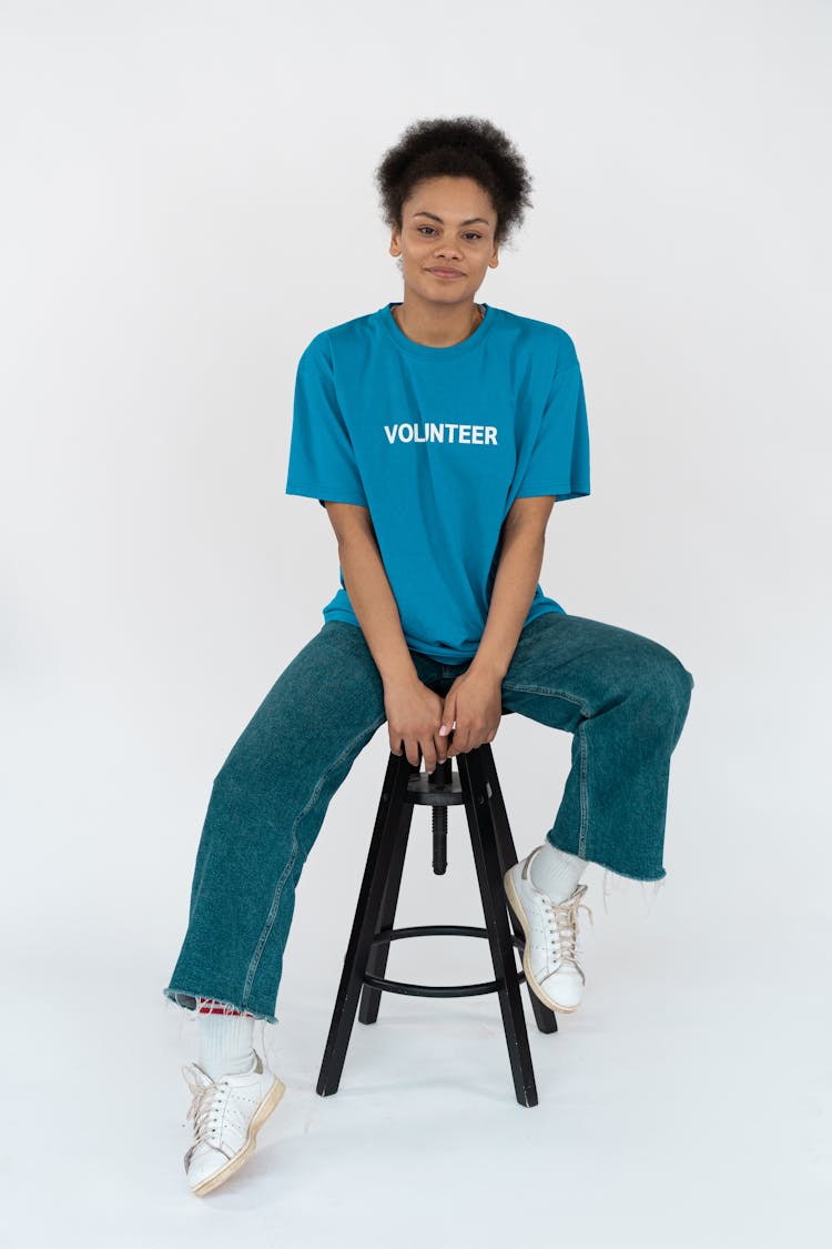 A Female Volunteer In Blue Shirt Sitting On A Chair