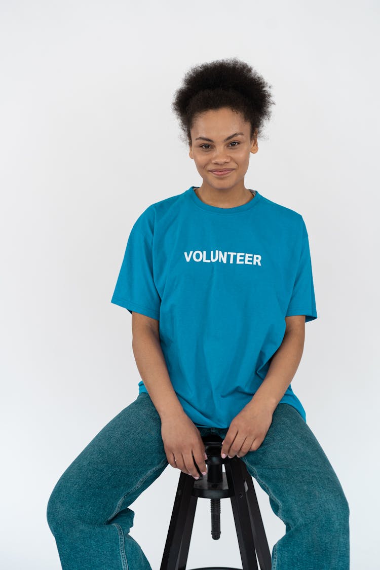 A Female Volunteer In Blue Shirt Sitting On A Chair