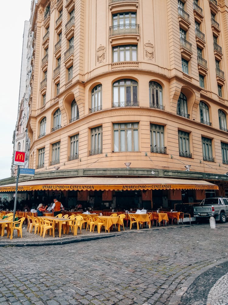 Street Corner With Cobblestone And Yellow Plastic Chairs In Front Of Cafe