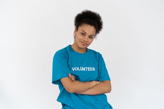 Portrait of a smiling woman in blue with arms crossed, embodying confidence and volunteerism.