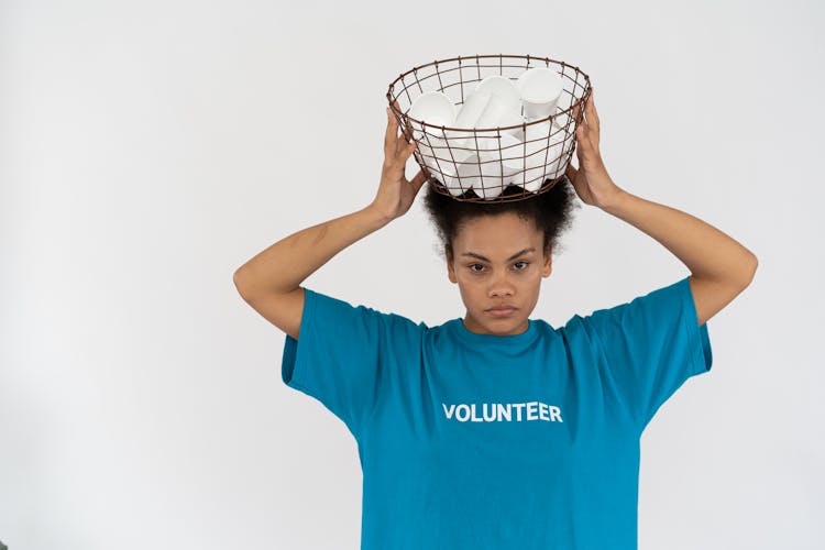 A Woman In Blue Shirt Holding A Basket Of Plastic Cups