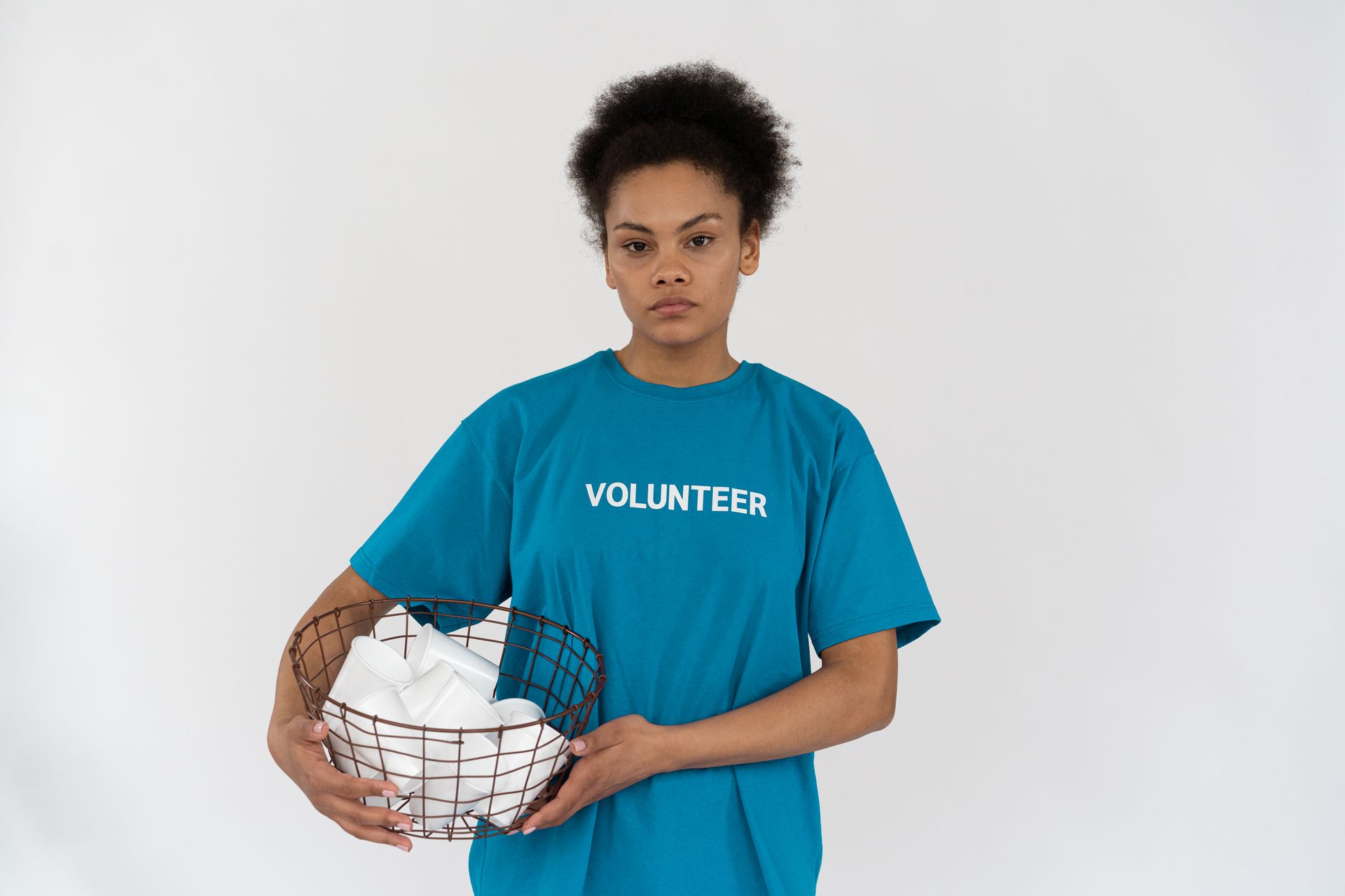 Young volunteer with basket of disposable cups, promoting recycling and environmental conservation.