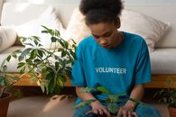 A young woman in a volunteer shirt focusing on planting indoors.