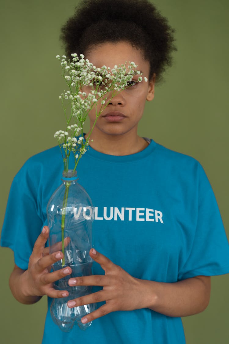 Woman In Blue Shirt Holding A Plant In A Plastic Bottle 