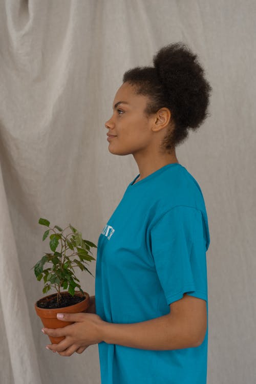 A Woman in Blue Shirt Holding a Potted Plant