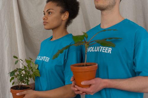 Free Two volunteers holding potted plants highlighting environmental conservation efforts. Stock Photo