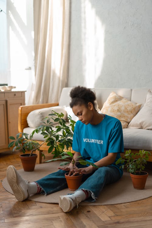 Free Woman in Red Crew Neck T-shirt Sitting on Blue Sofa Stock Photo