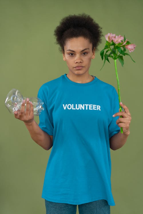 Free A Woman in Blue Shirt Holding Plastic and Flowers Stock Photo