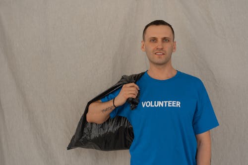 Man in Blue Crew Neck T-shirt Holding Black Plastic Bag