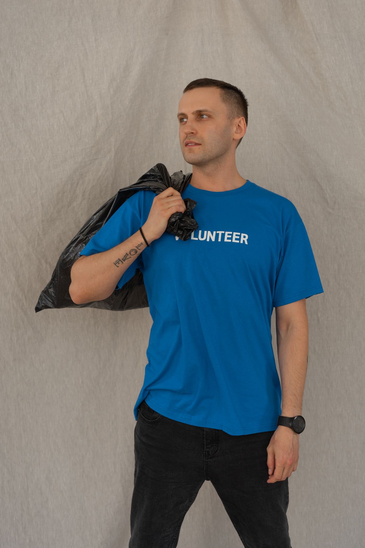 Volunteer in a blue shirt holding a full garbage bag on a collection route