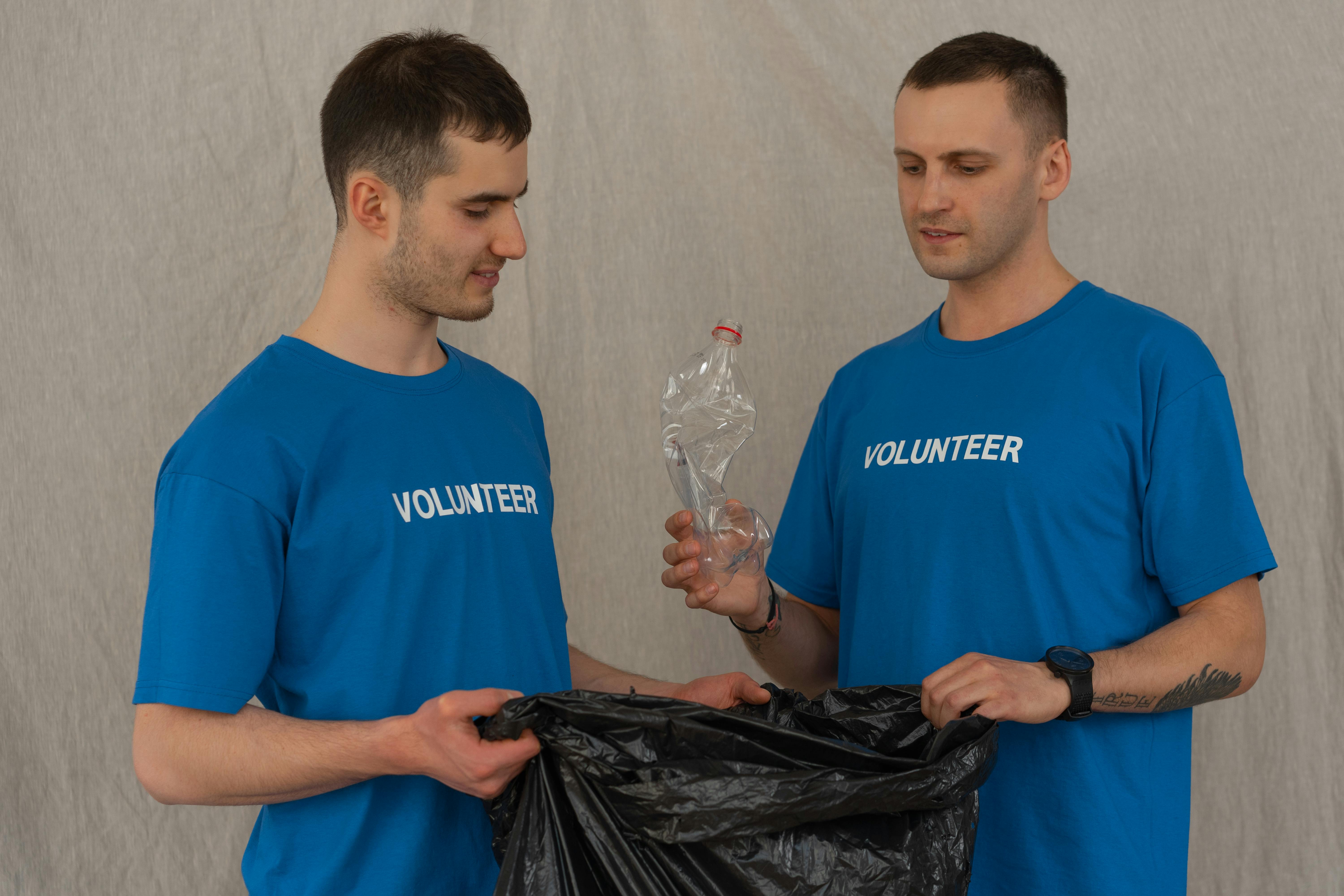 man in blue crew neck t shirt holding black plastic bag