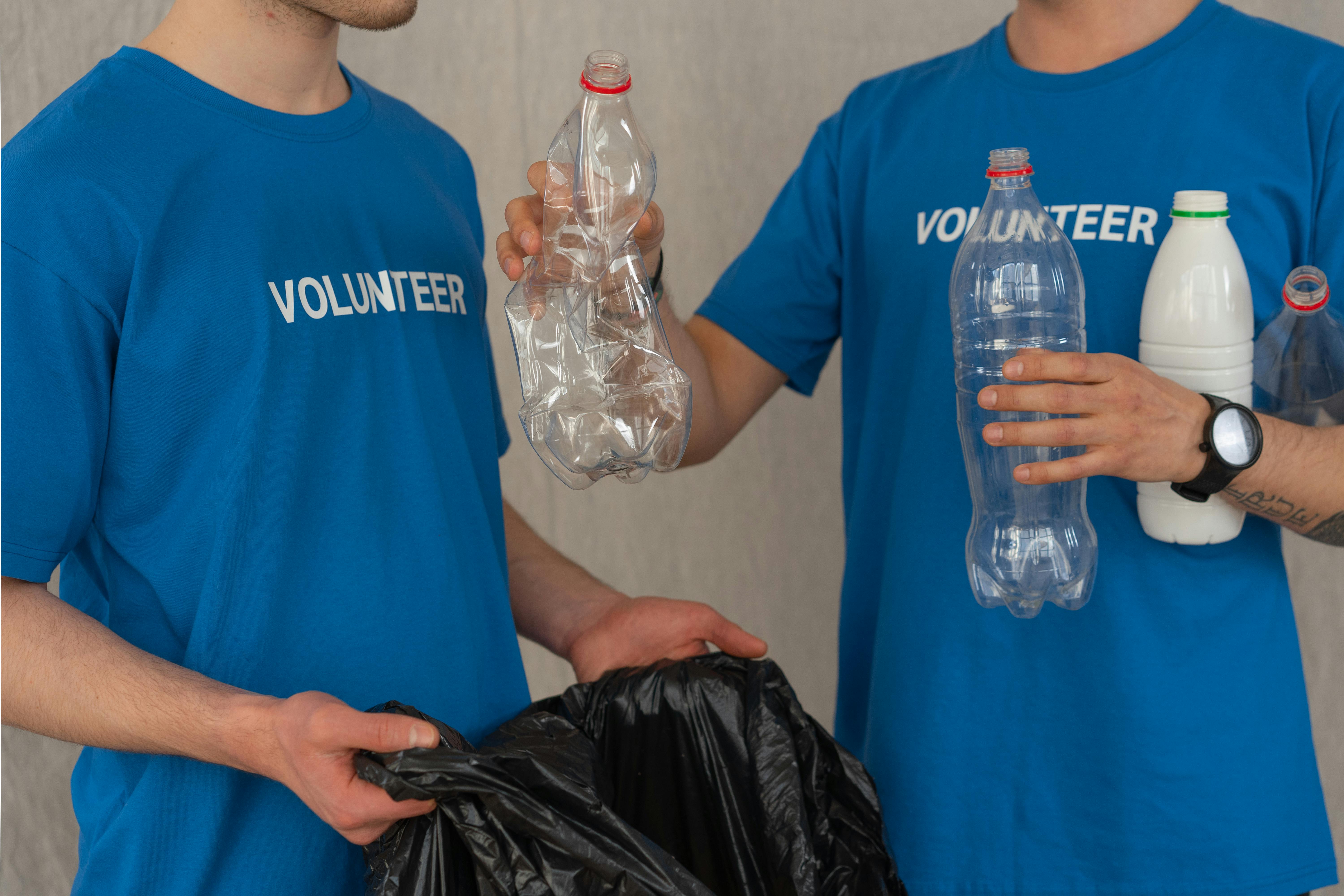 man in blue crew neck t shirt standing beside black plastic bag