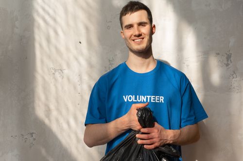 Free Smiling volunteer holding a garbage bag during a community cleanup effort. Bright and positive environmental action. Stock Photo