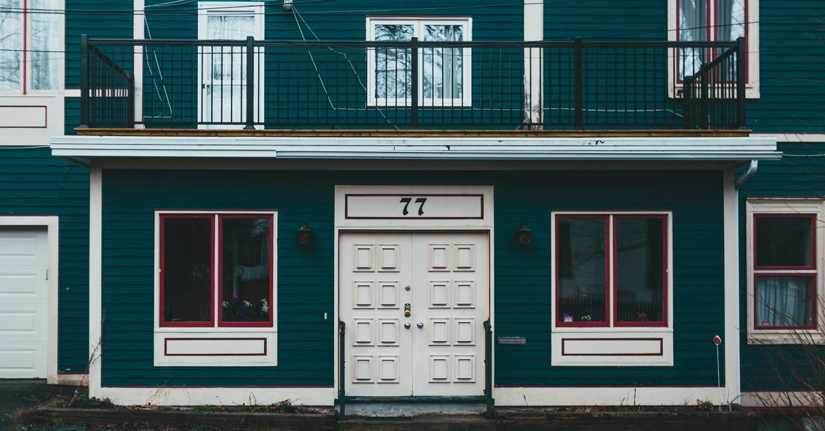 Facade of blue wooden building with white doors and windows located in residential district in town in daylight
