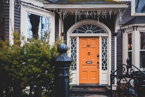 Free Exterior of contemporary wooden orange door and black cast iron gates to house Stock Photo