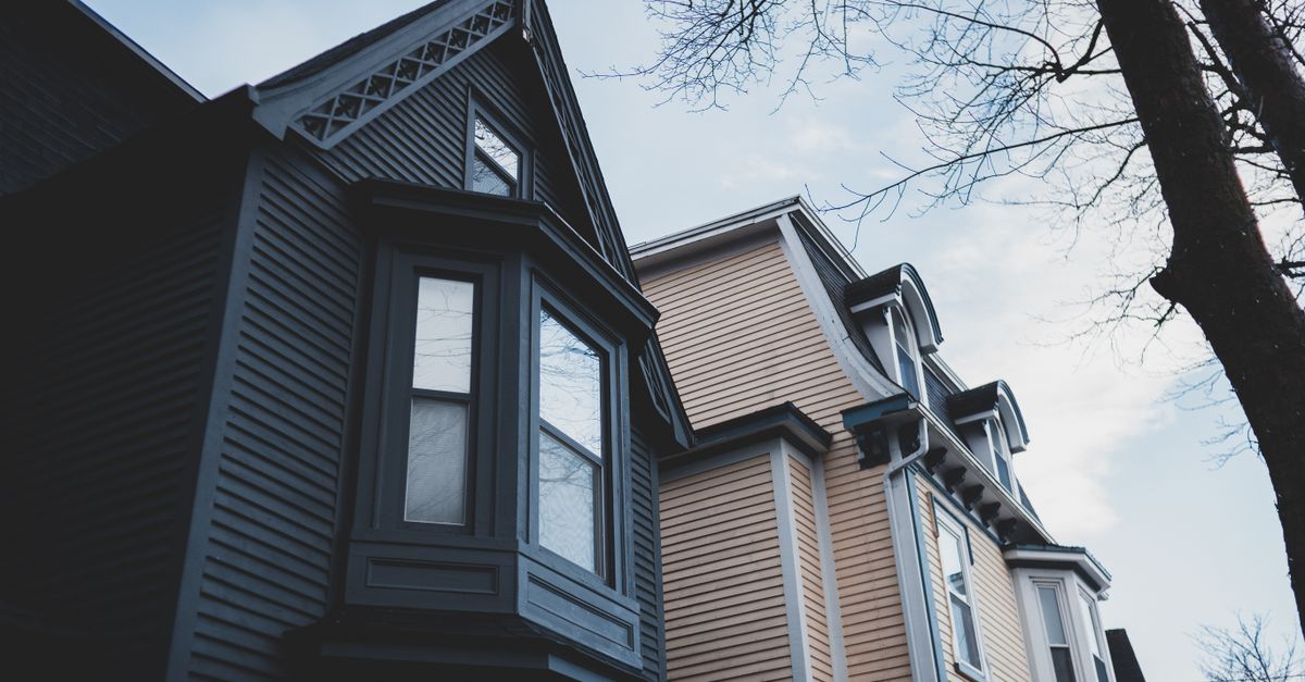 From below of exterior of modern residential building with windows and attic trimmed with dark gray wooden siding